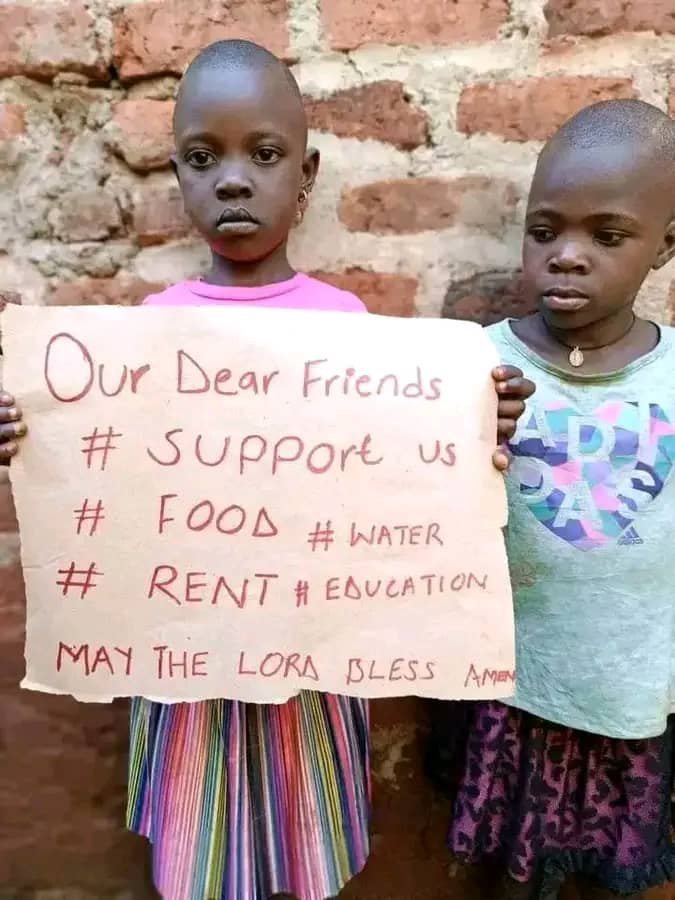 Children holding a handmade support sign beside a brick wall